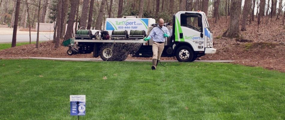 TurXpert worker fertilizing lawn with sprayer in Duluth, GA.